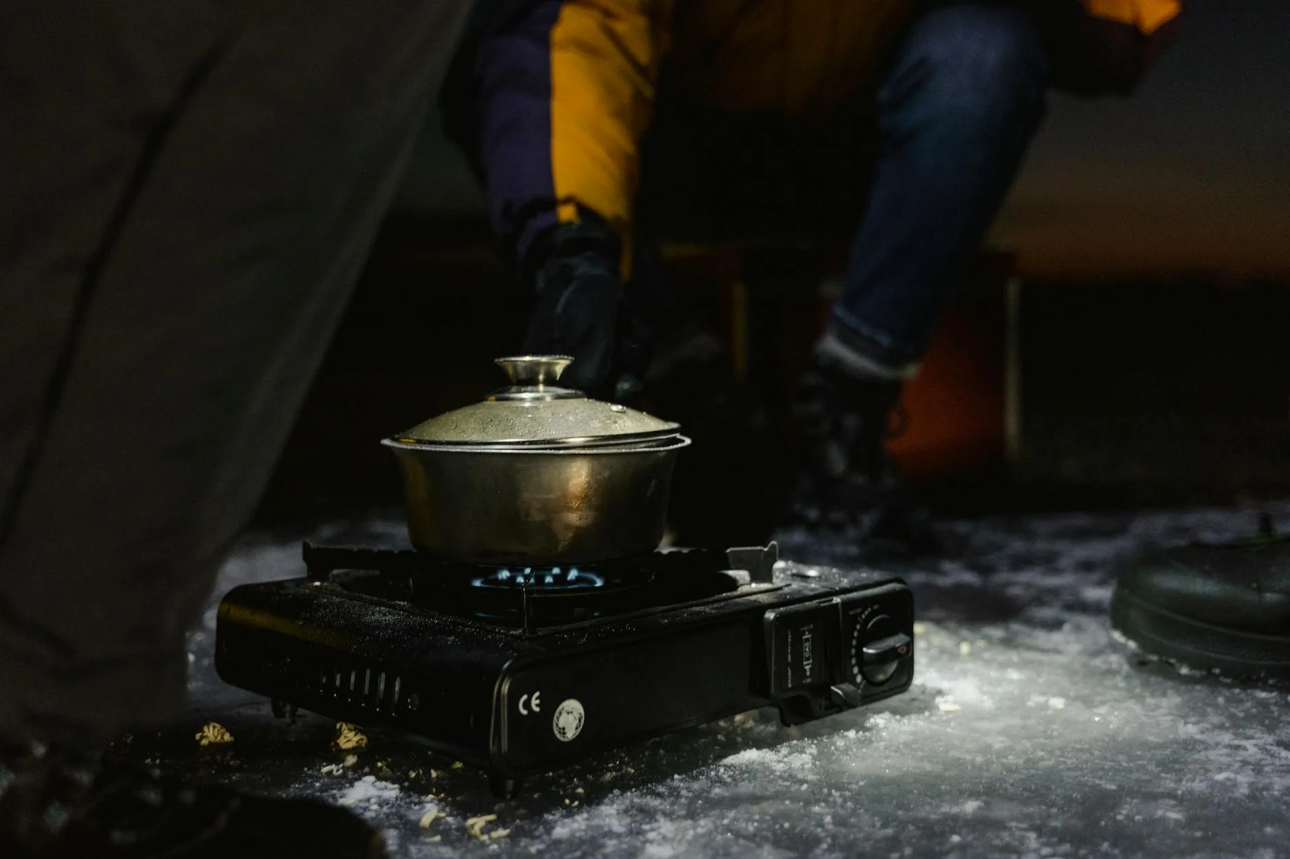 Compact camping stove heating pot outdoors in wilderness