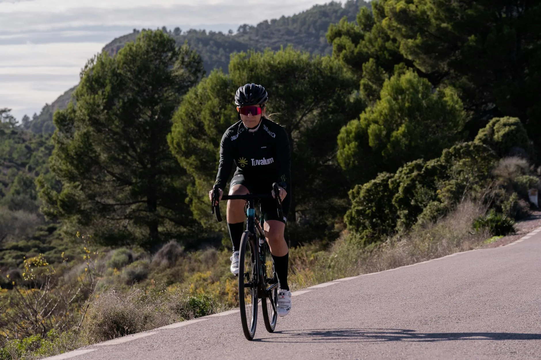 Cyclist riding a road bike through scenic countryside hills