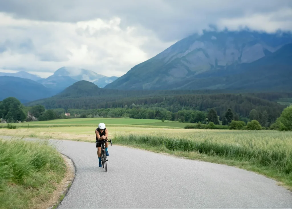 Cyclist riding along a winding rural road through lush green countryside