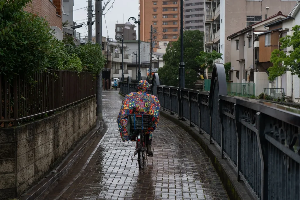 Cyclist commuting in rain wearing a waterproof jacket on a city street